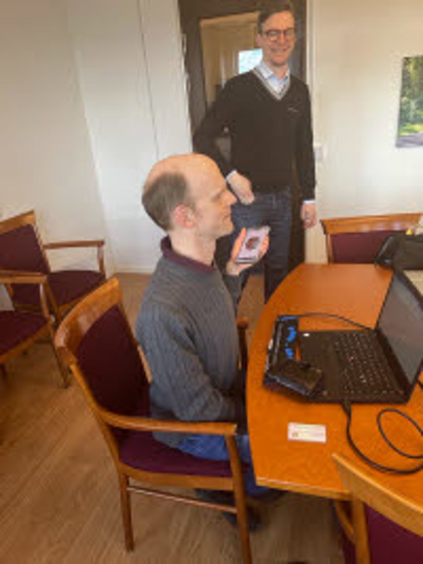 Man sitter vid dator och en man står bredvid