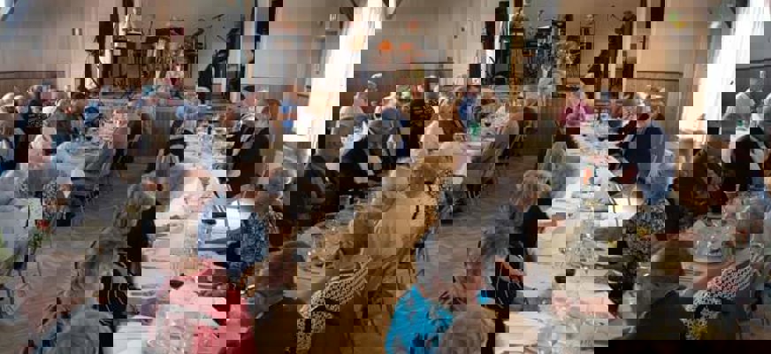 En grupp människor sitter och äter vid ett långbord.