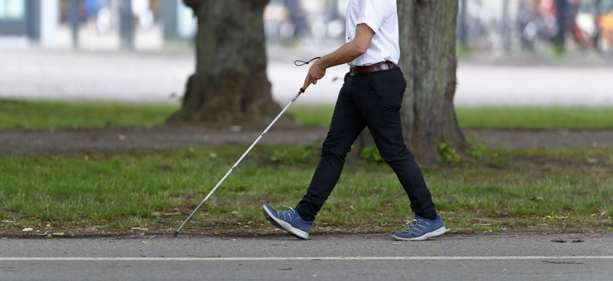 Person går med käpp i stadsmiljö