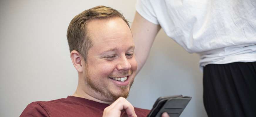 Man ler och tittar på telefon