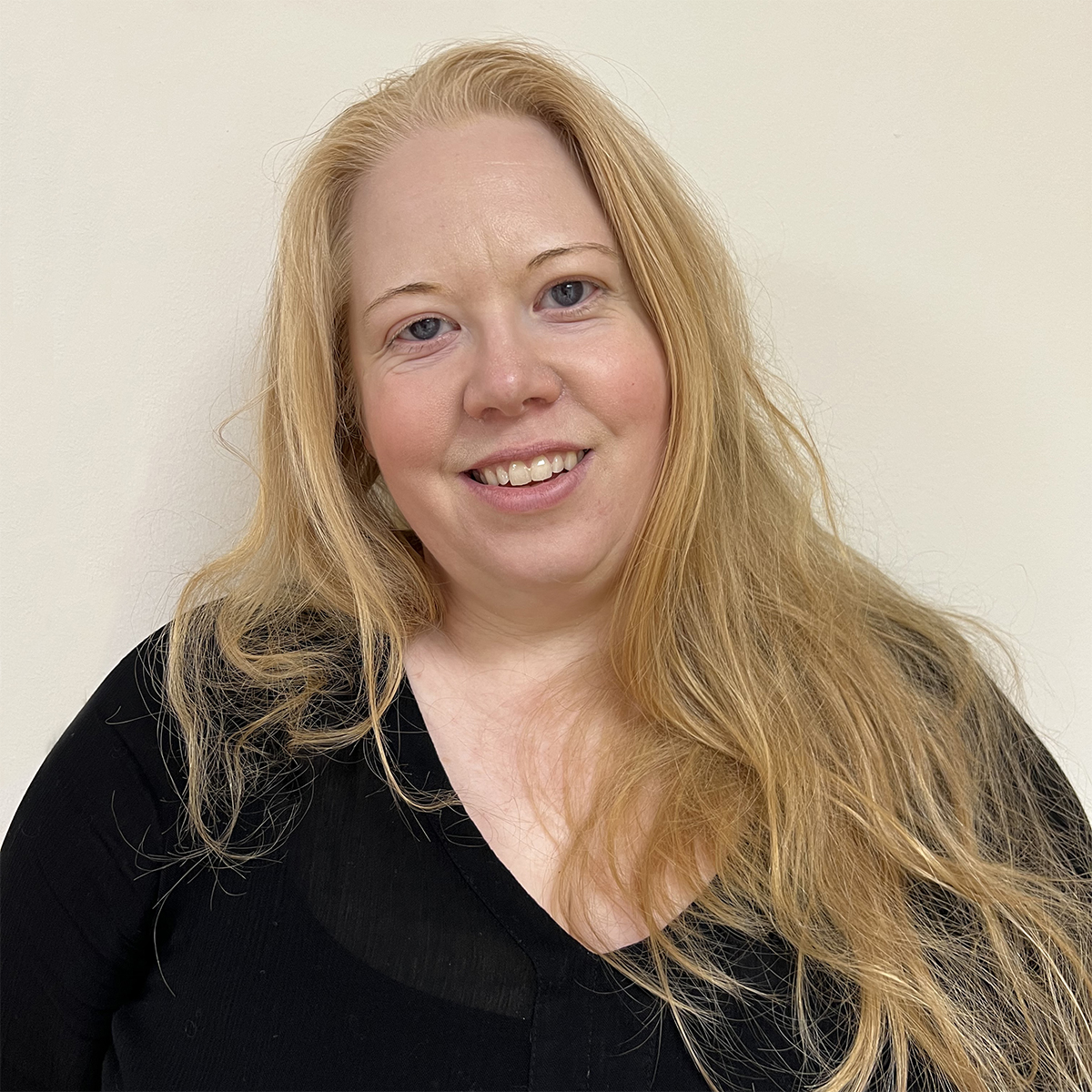Leende kvinna i 40-årsåldern med långt blont hår och svart tröja.