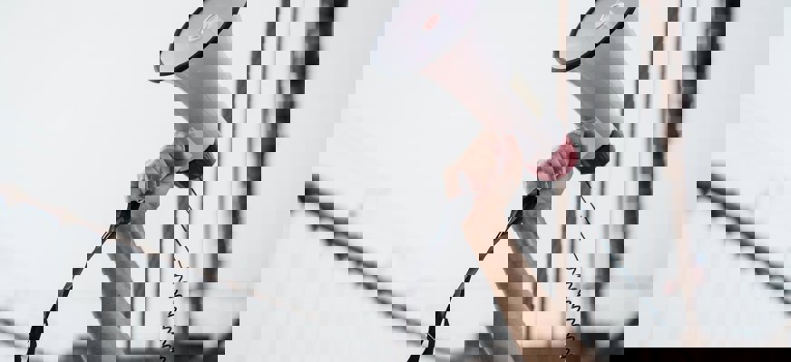 En arm håller upp en vit megafon i luften.