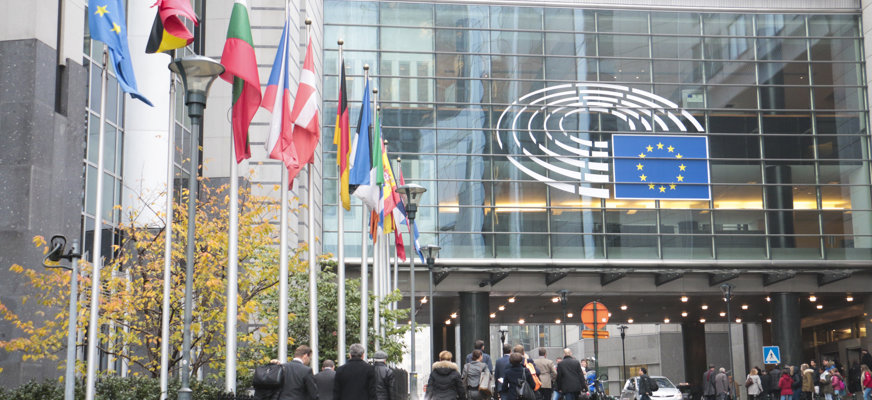 Europeiska unionens parlamentsbyggnad omgiven av europeiska flaggor.
