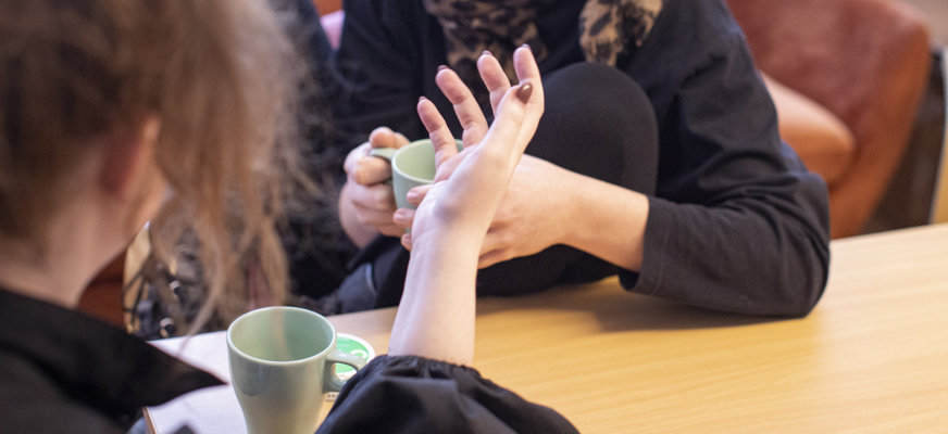 Två kvinnor samtalar engagerat över en kopp kaffe.