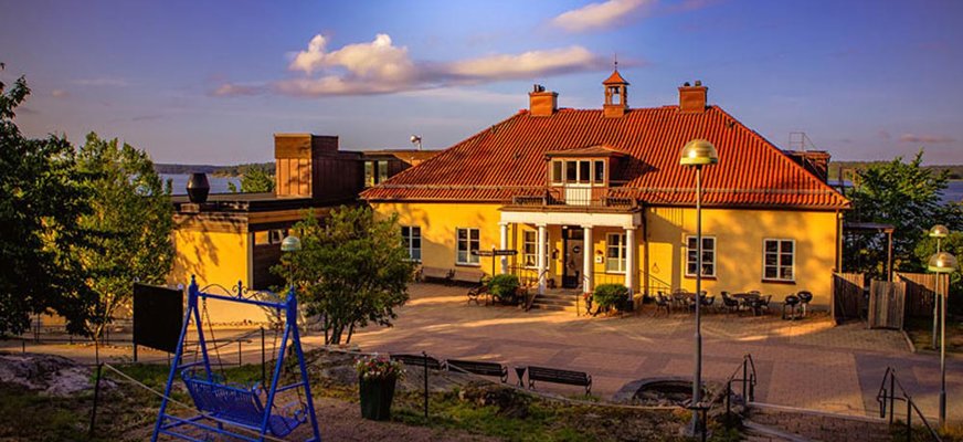 Huvudbyggnaden på Almåsa havshotell är en ljusgul herrgård med vita pelare vid ingången. Den ligger nära Östersjön och det syns på bilden.