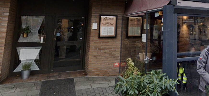 bilden visar restaurangens entre. En rödgul tegelbyggnad med en svart inglasad terass på utsidan.