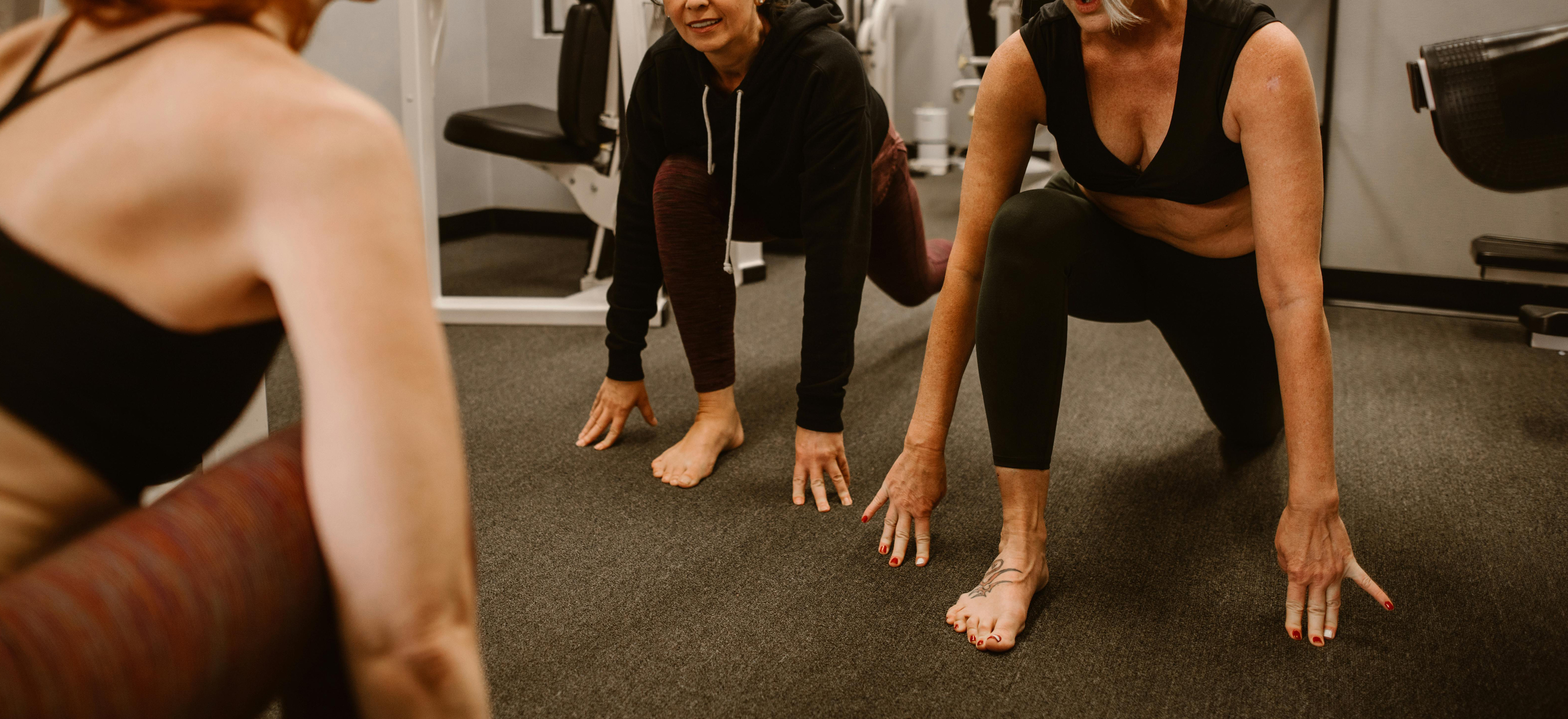 Tre äldre kvinnor som tränar tillsammans inomhus.