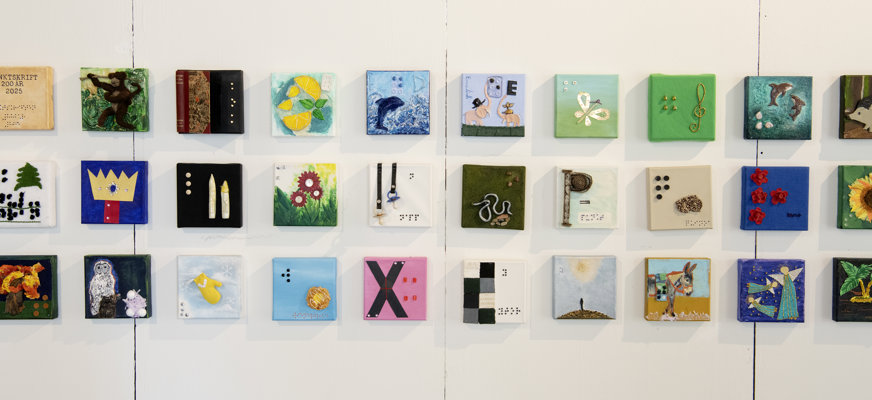 Massa små konstverk i form av kvadrater som bildar ett rutmönster med tre rader.