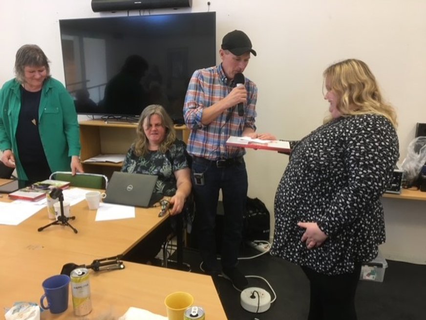 SRF Uppsala läns årsmöte 2023. Tomas Wallén överlämnar en chokladask till avgående styrelse- ledamot Ida-Maria Engberg.