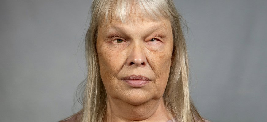 En närbild av en kvinna i 50-års-åldern som tittar rakt fram. Hon har långt, ljust hår med lugg och ett neutralt ansiktsuttryck. Bakgrunden är ljus och avskalad.