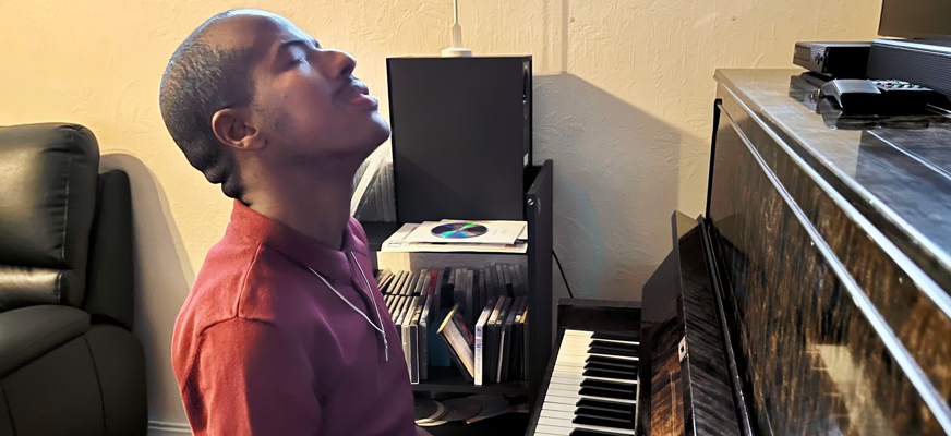 En man sitter och spelar på ett piano.