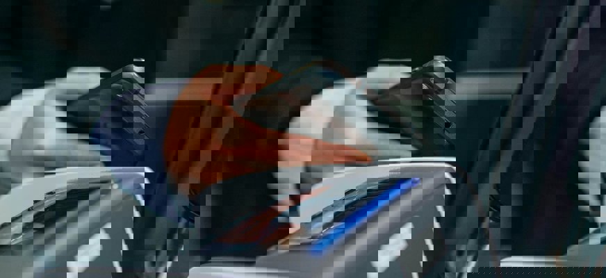 Närbild på en person som betalar med "blipp". Personen håller sin mobiltelefon mot en kortterminal.