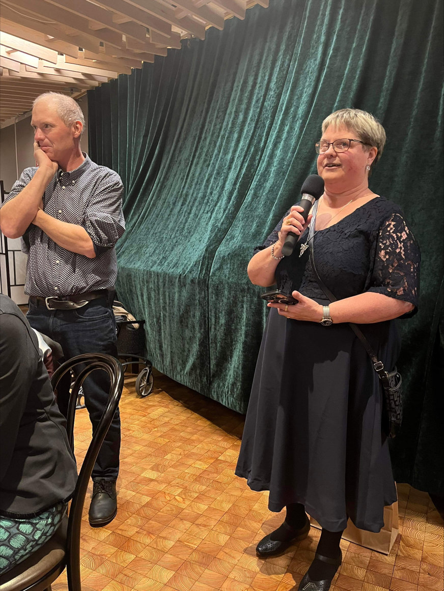 Christina Lundgren, ordförande för SRF Gävleborg talar på jubileumsfesten. Tomas Wallén står bredvid och lyssnar.