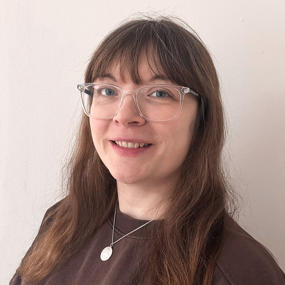 Portättbild av Katarina Viklund. Hon har rakt brunt hår som faller över axlarna. Hon har en lång rak lugg och glasögon med tjocka genomskinliga bågar. Hon är klädd i en brun tröja med ett silverhalsband över.