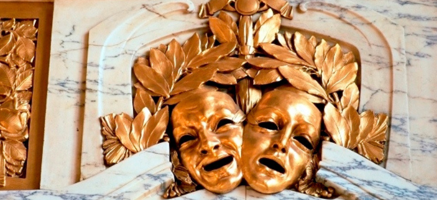 Två guldfärgade ansiktsmasker, ena glad och den andra ledset