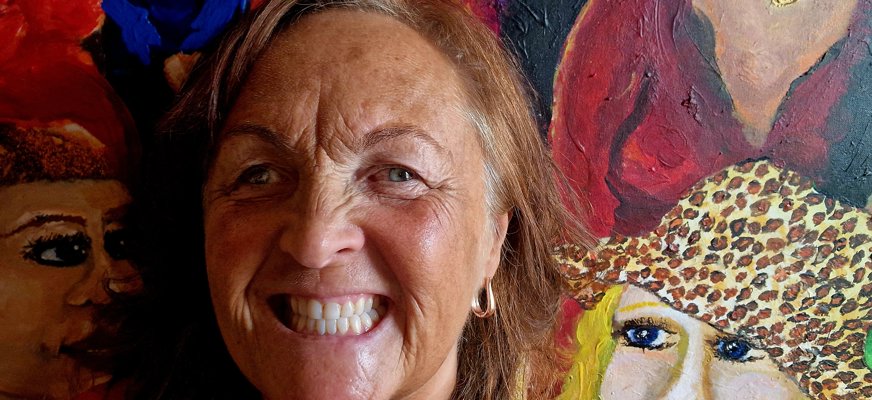 Porträtt föreställande Monicka framför en färgstark tavla