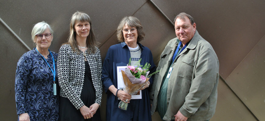 Tre kvinnor och en man står på rad. Anna-Karin Wikman har axellångt hår, håller i en blombukett och ler stort mot kameran.