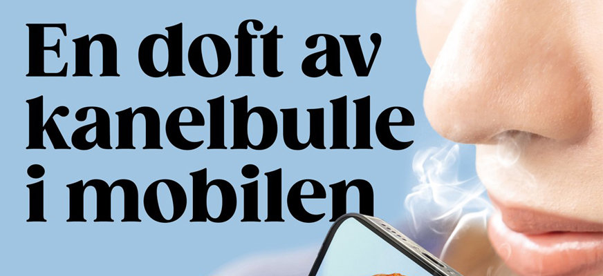 Reklambanner kvinna luktar i sin telefon, rök kommer ut ur högtalarhålen. Text: "En doft av kanelbulle i mobilen". 