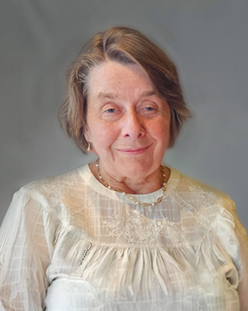 Porträttbild Monica Fredriksson: Äldre kvinna med kortklippt ljust hår och vit blus.