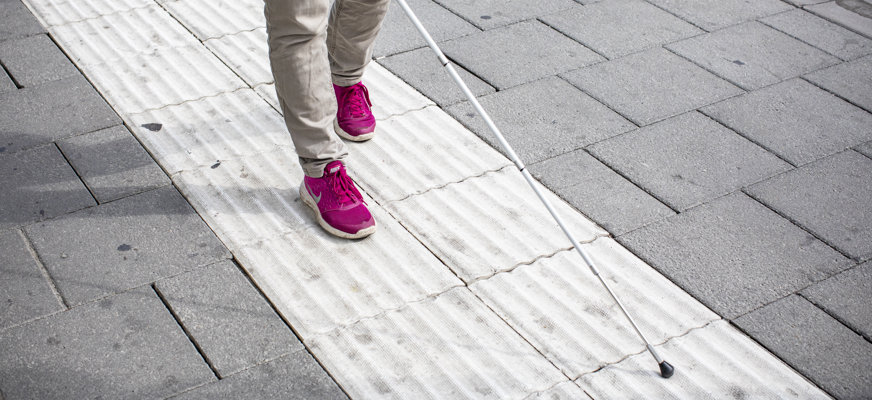 Person med käpp följer taktilt ledstråk