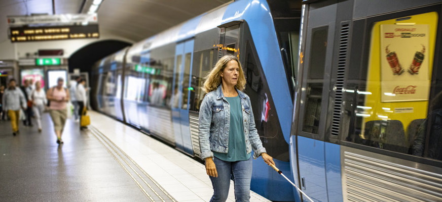 Kvinna med käpp vid tunnelbanetåg