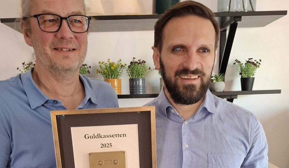 Johan Lunner tillsammans med Fatmir Seremeti. Johan håller i sin inramade guldkassett och båda ler mot kameran.