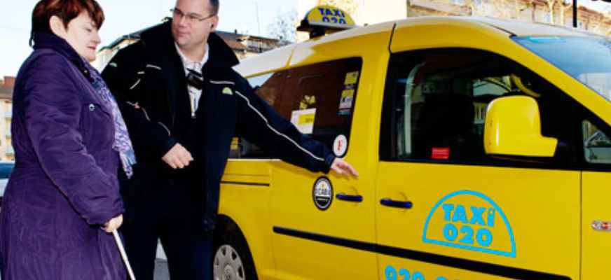 En kvinna får hjälp av en man att kliva in i en taxibil