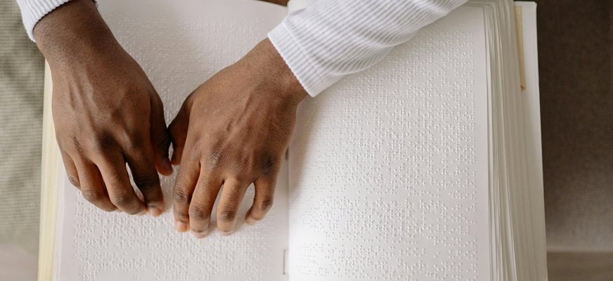Närbild på två händer som läser punktskrift.