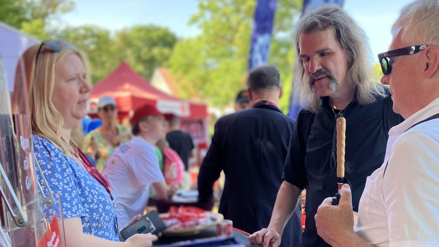 Fredrik Stockhaus och Niklas Mattsson samtalar med regionpolitiker från Gotland. De står vid ett rött podium utanför ett tält.