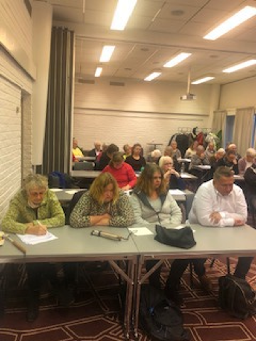 Styrelseledamöterna Eva Norén Agell och Ida-Maria Engberg sitter vid ett bord bredvid ledsagare Milena Michalek och ombudsman Wieslaw Wasowski. I bakgrunden syns övriga mötesdeltagare vid olika bord.