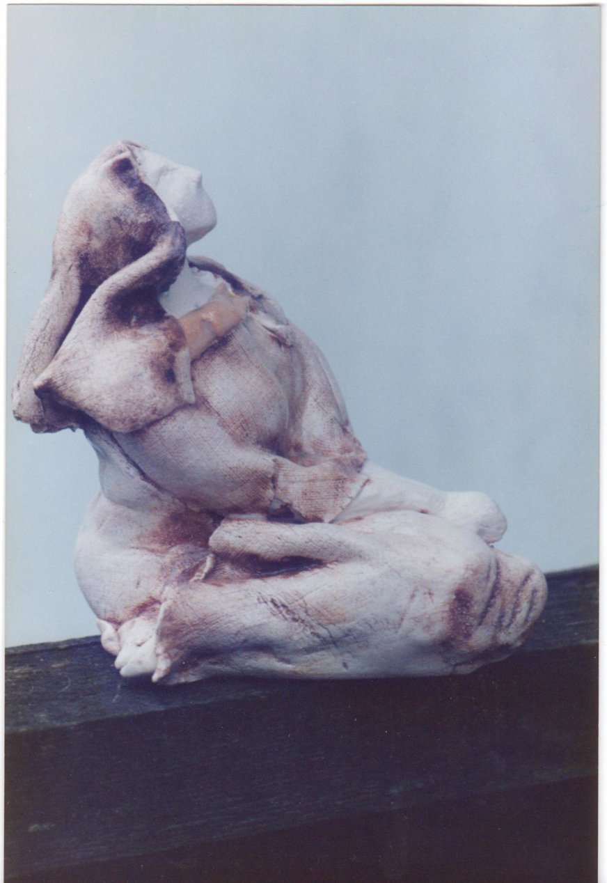 Keramik figur föreställande en kvinna med huckle som sitter och tittar uppåt.