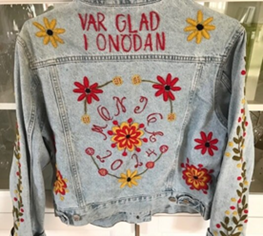 Grå tröja med texten "Var glad i onödan" broderad.